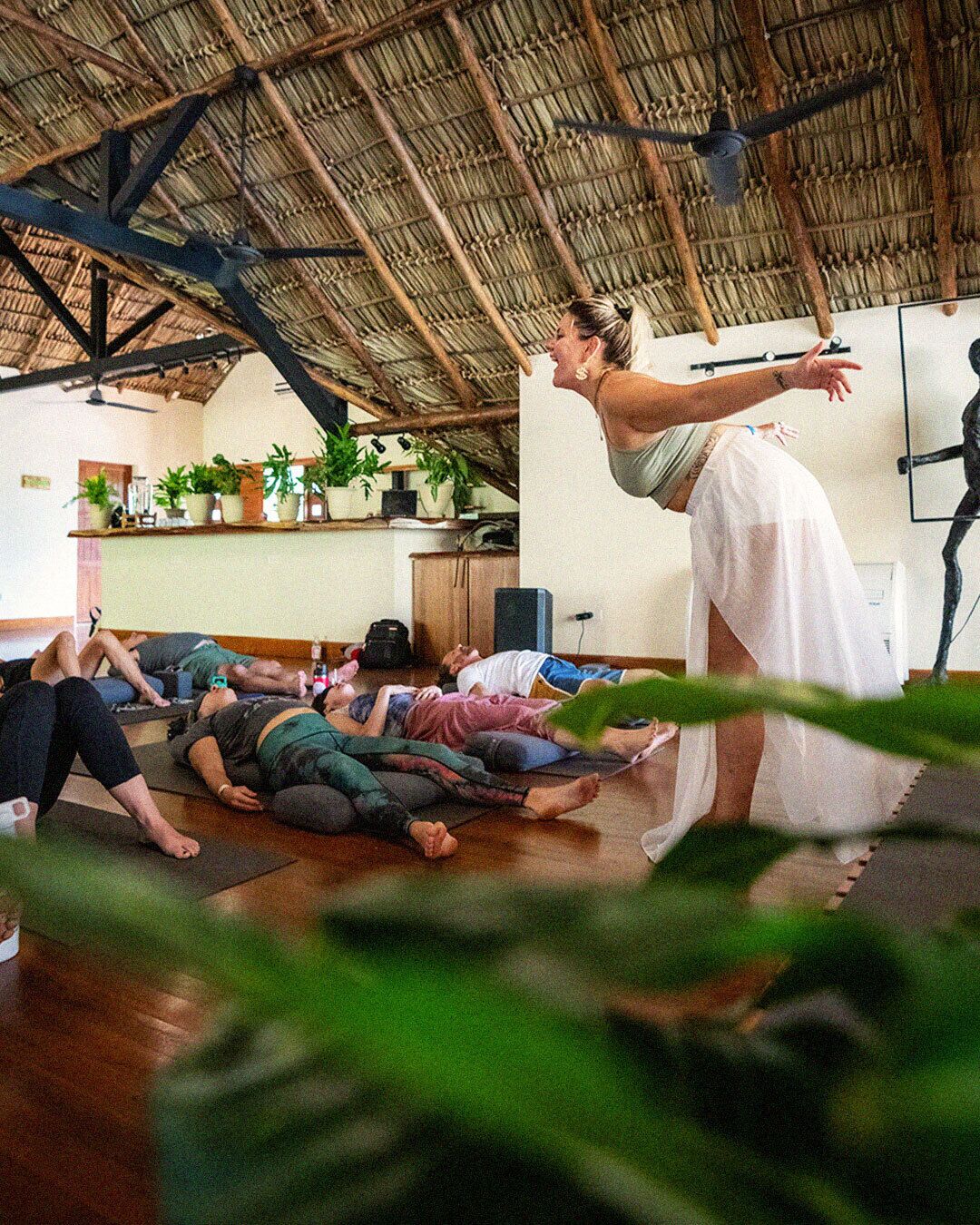 Ein Yoga-Kurs in einem Raum mit hoher Decke und einem Strohdach.