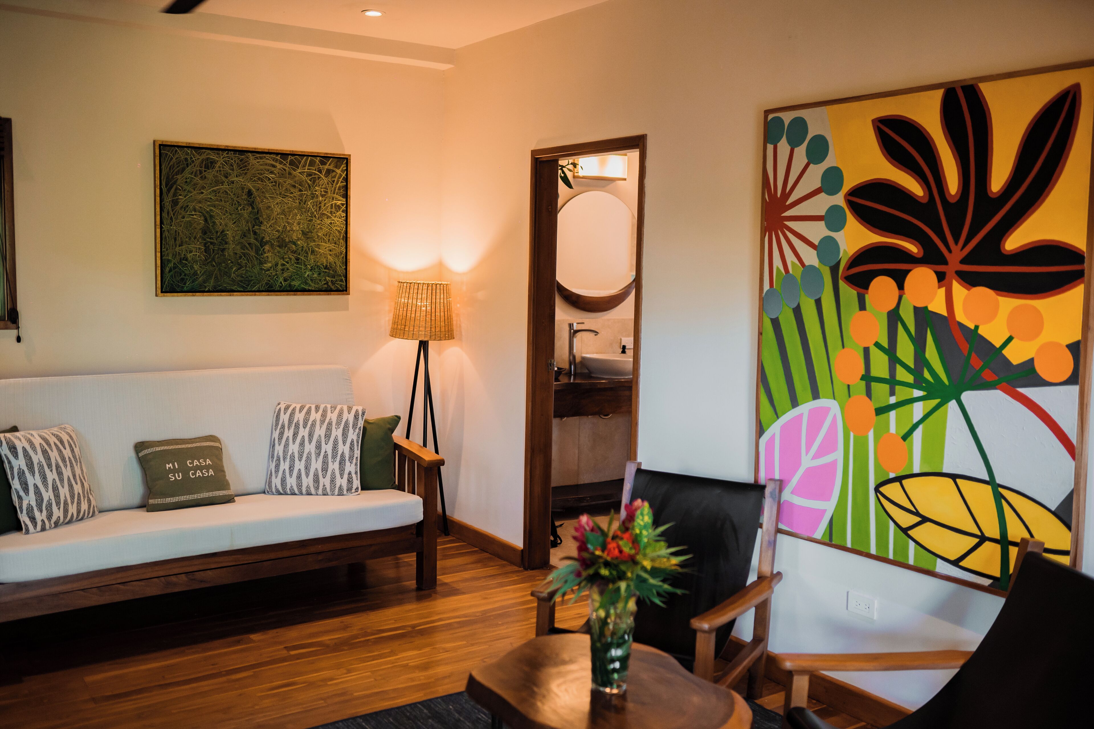 Sala de estar com sofá, poltrona, abajur e um quadro.