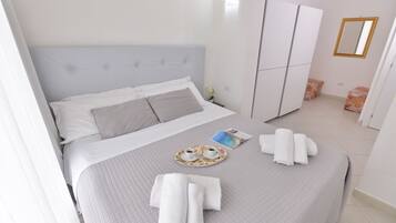 A neatly arranged bedroom with a bed, a wardrobe, and a tray with towels and a magazine.