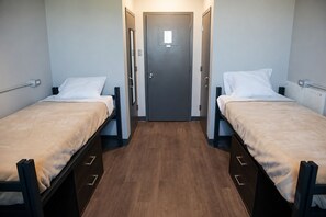 Una stanza con due letti, una porta e un termosifone.