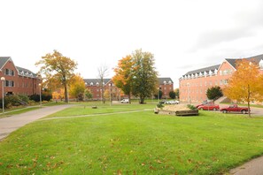 A grassy courtyard with brick buildings, a paved path, and parked cars. - Dalhousie University Agricultural Campus (Bible Hill)