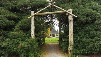 A wooden archway leading to a gazebo in a forested area.