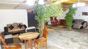 Un salón acogedor con un sofá, una mesa de madera y sillas. Una planta grande se encuentra en el centro.