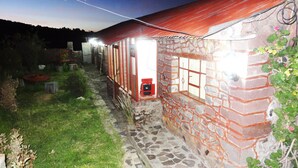 Un edificio de piedra con techo rojo y un buzón pequeño rojo.