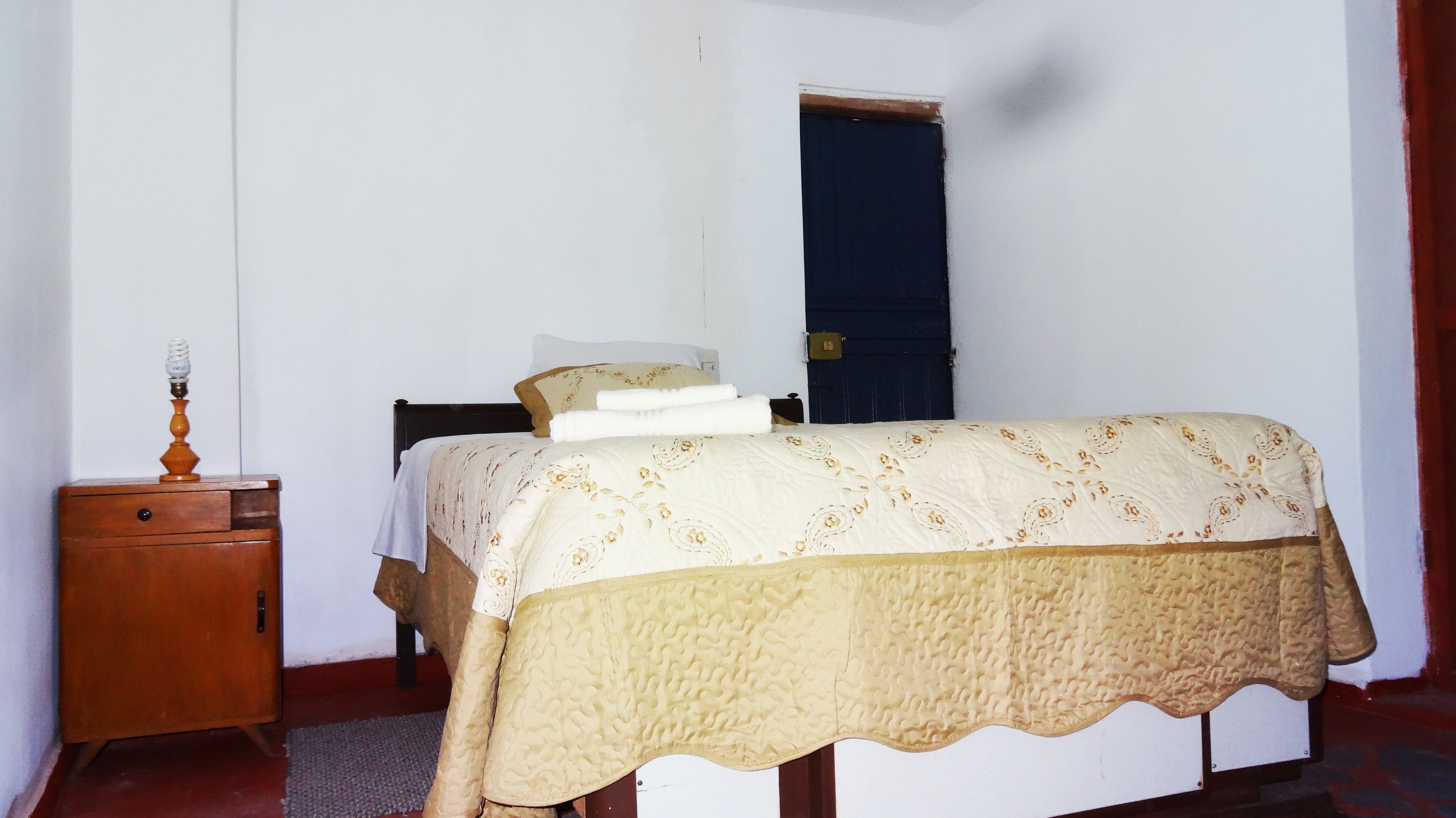 A bedroom with a bed, a nightstand, a lamp, and a door.