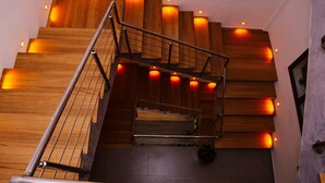 Una escalera moderna con escalones de madera y barandillas de metal, iluminada por luces empotradas.