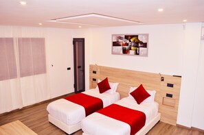 Une chambre d’hôtel avec deux lits, une tête de lit en bois, un tableau au mur et une porte.