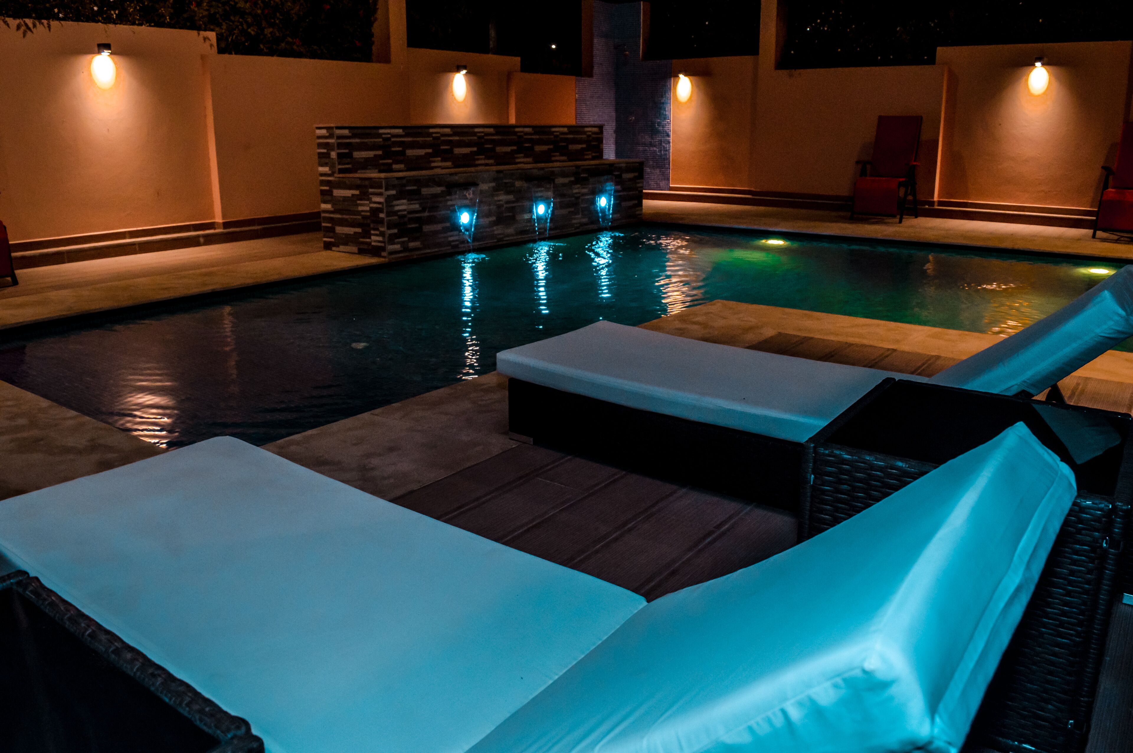 A pool area with lounge chairs and a built-in bench.
