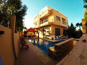 A modern two-story building with a swimming pool, sun loungers, and a red canopy. - Villa Arabic House Pool & SPA (Marrakech)