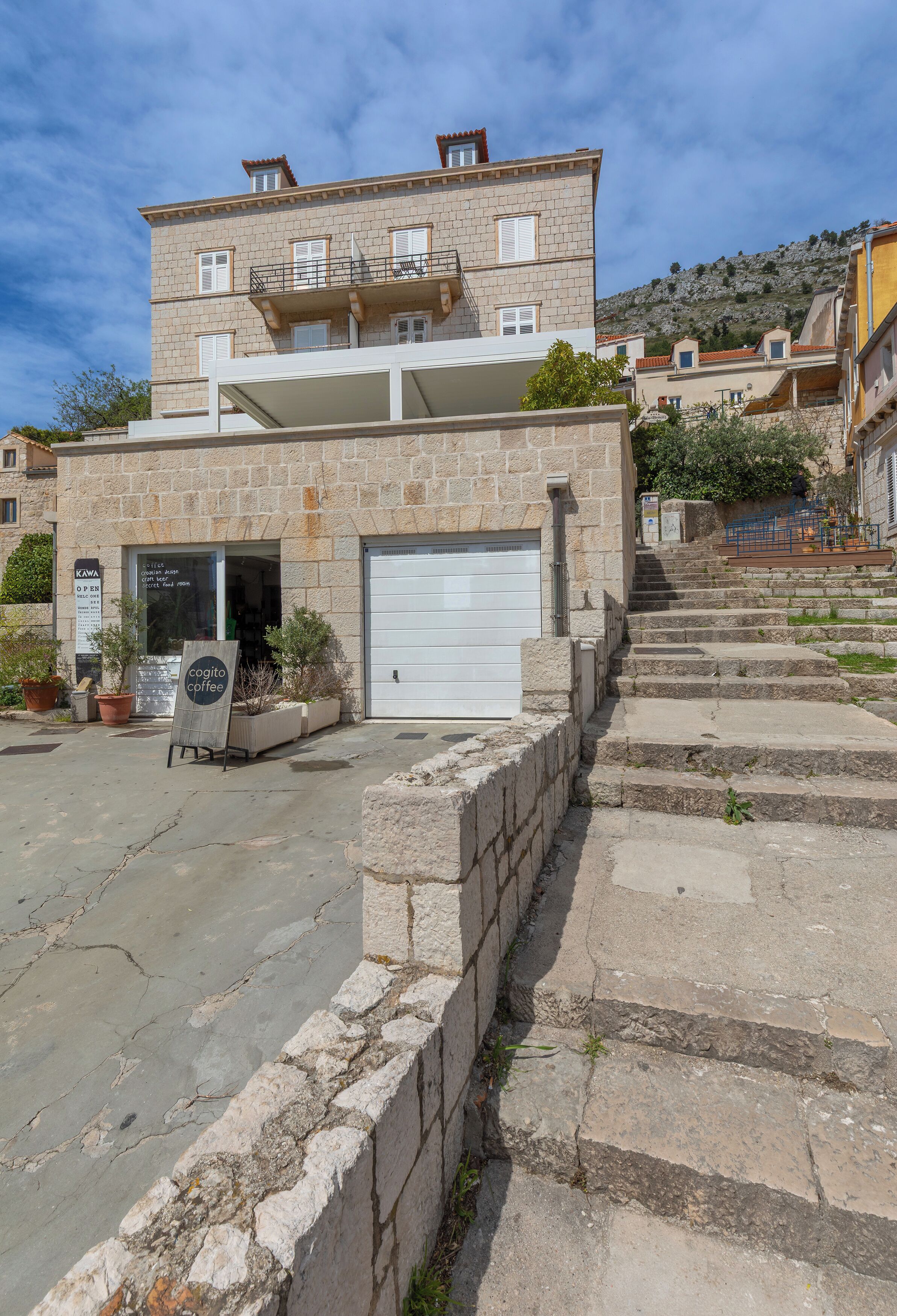 Un bâtiment à deux étages doté d’une porte de garage, d’une enseigne et d’un escalier menant à l’entrée.