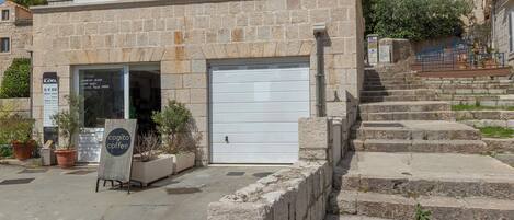 Un bâtiment à deux étages doté d’une porte de garage, d’une enseigne et d’un escalier menant à l’entrée.