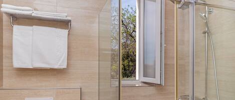 Une salle de bain moderne avec une douche à parois de verre, des toilettes et un porte-serviettes avec des serviettes pliées.