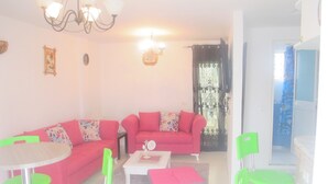 Una sala de estar con dos sofás rojos, una mesa de centro y sillas verdes.