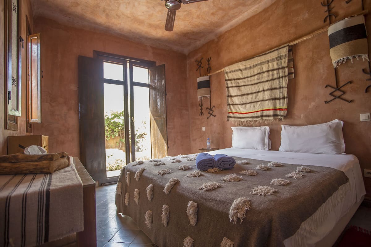 A room with a bed, a table, and a ceiling fan.