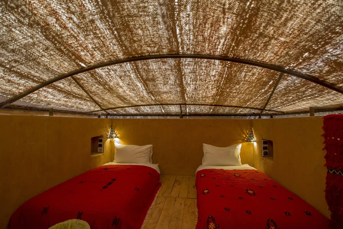 A room with two beds, a canopy, and wall-mounted lights.