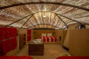 Ein zeltartiges Zimmer mit einem Bett, einer Kommode und einem roten Teppich.
