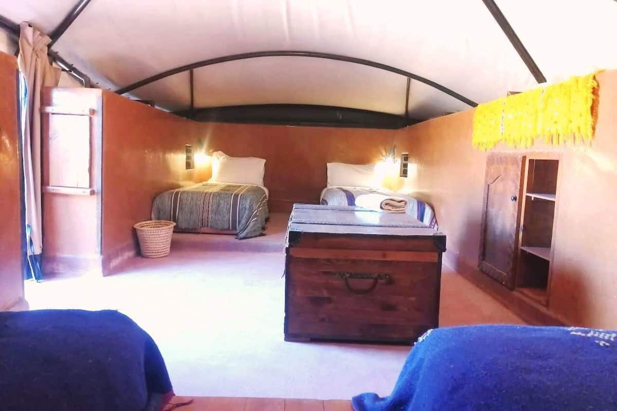 A tented room with a bed, a chest of drawers, and a small table.