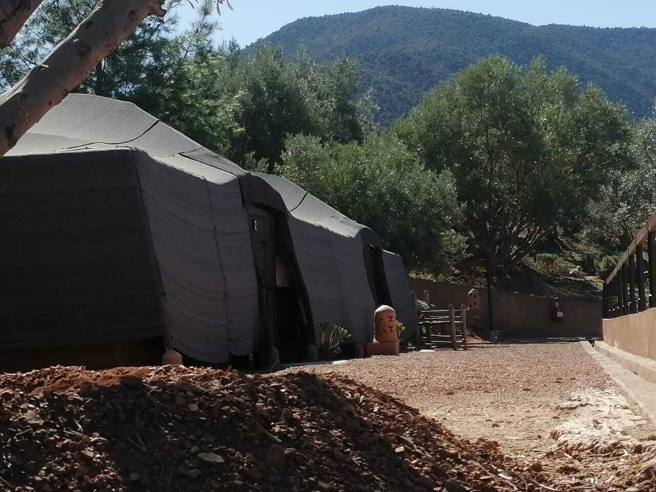 Ένα μέρος για κατασκήνωση με σκηνές και ένα χωμάτινο μονοπάτι που οδηγεί σε μια πύλη.