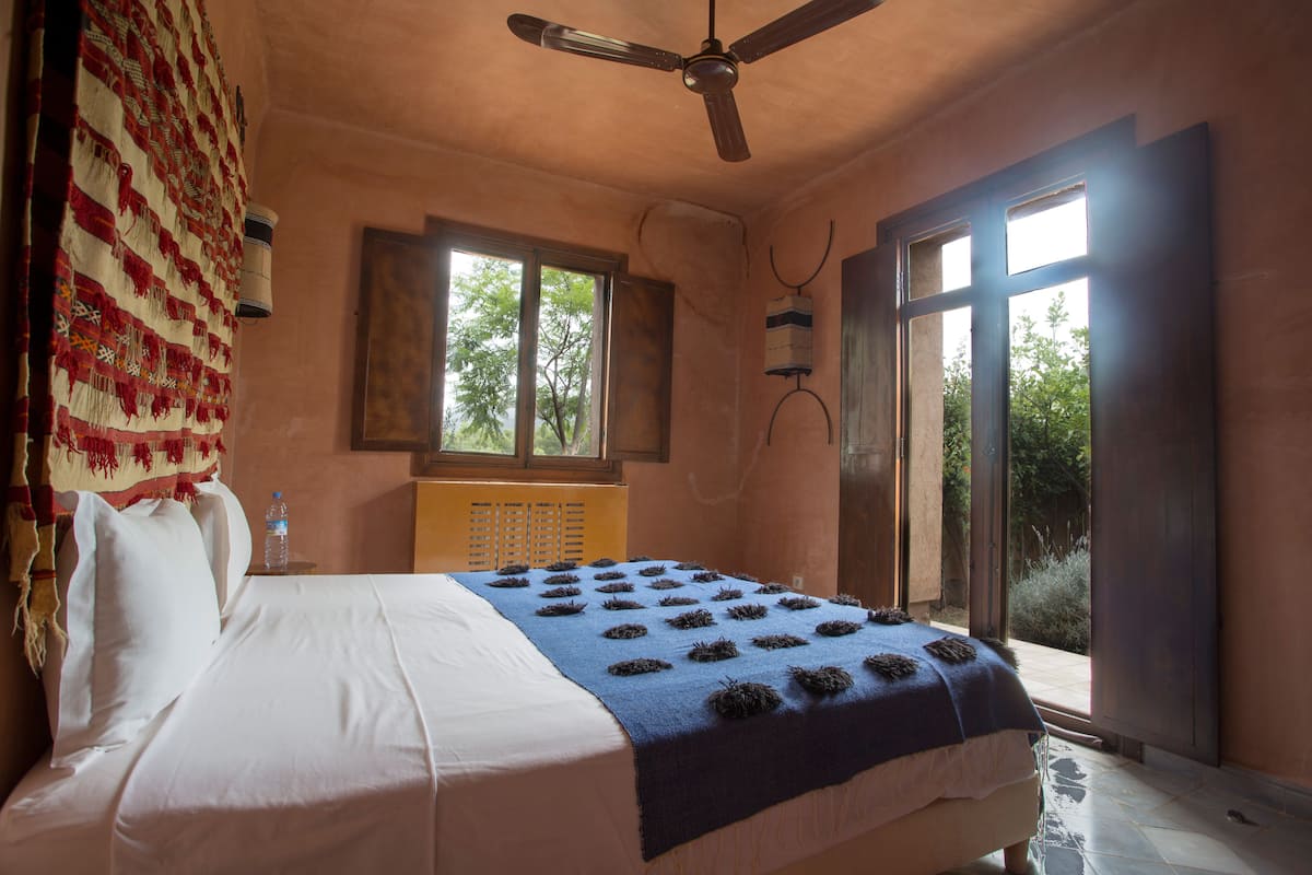A bedroom with a bed, a ceiling fan, a window, and a door.