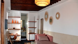 A living room with a sofa, coffee table, and decorative mirrors. There is a small kitchenette in the background. - Riad Dar Dar (Rabat)