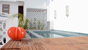 A wooden deck with a swimming pool, white walls, and decorative plants. - Riad Dar Dar (Rabat)