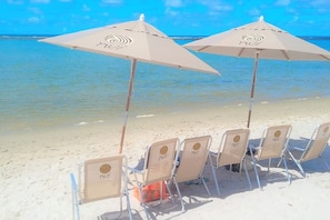En la playa, arena blanca, sillas reclinables de playa, sombrillas