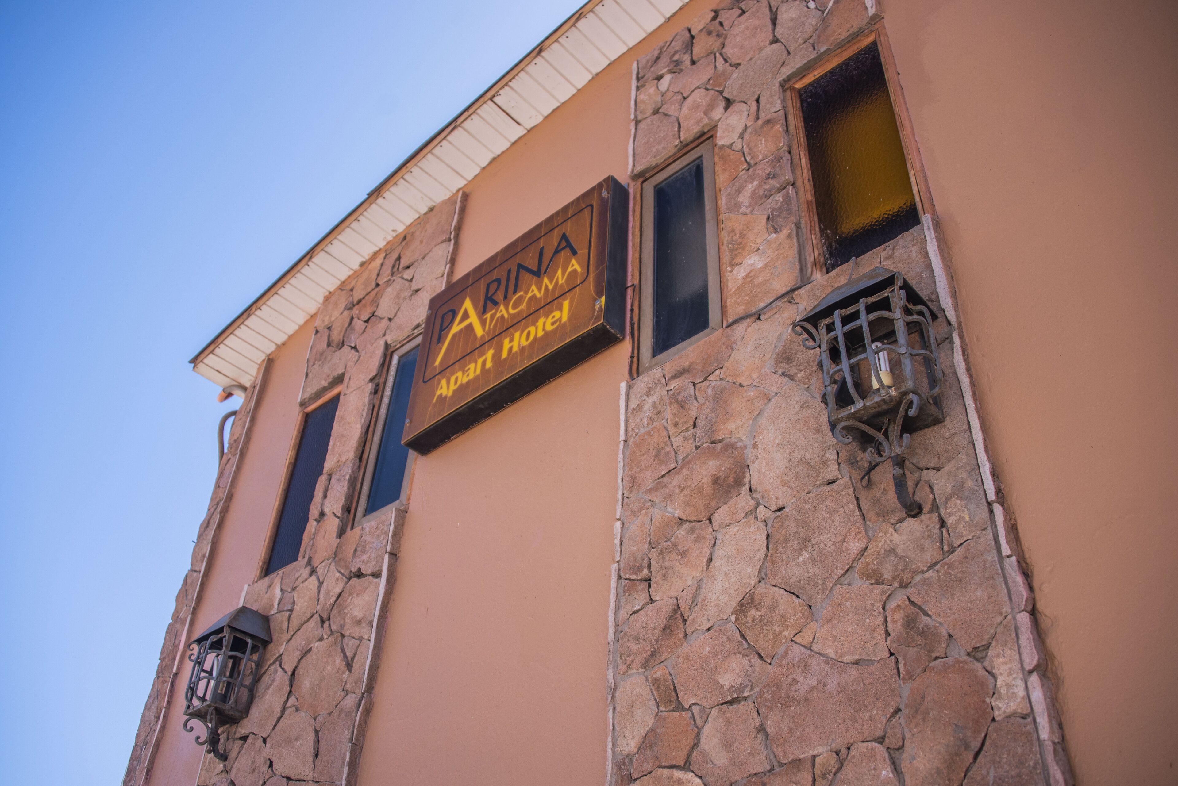 A stone facade with a sign for "PARINA ACAMAPA Apart Hotel".