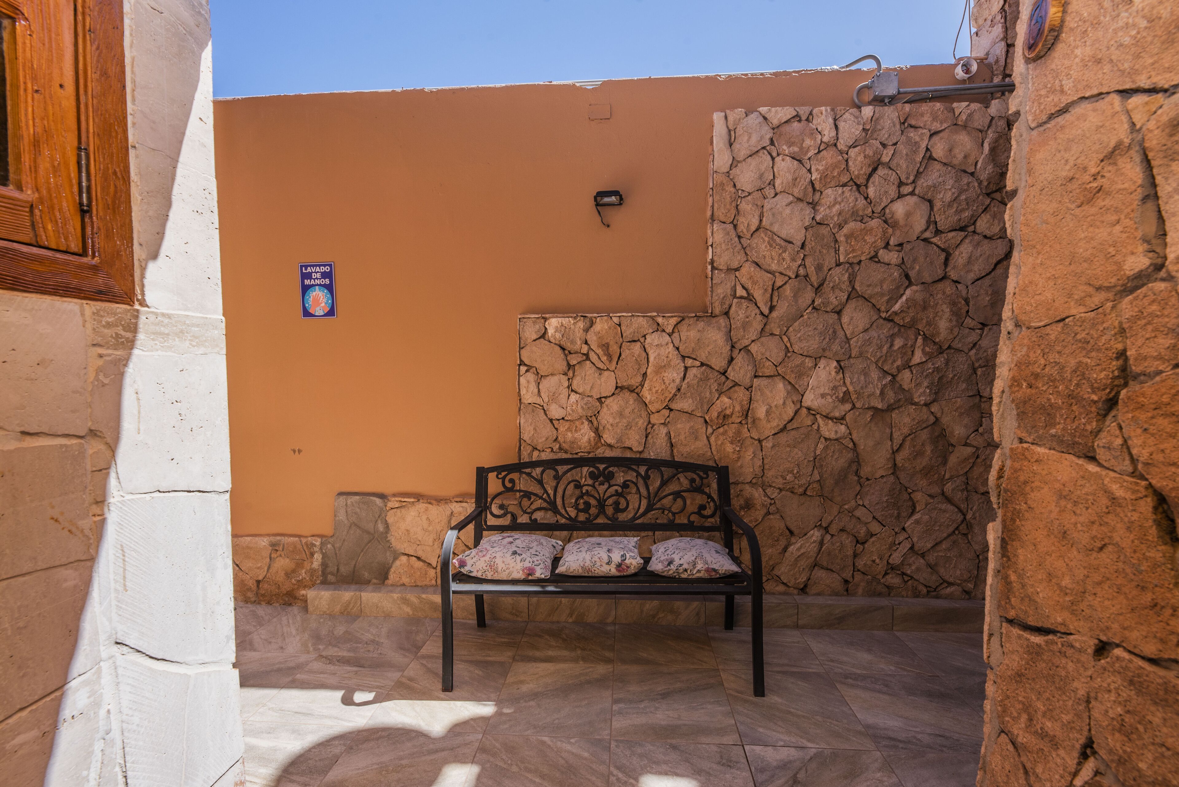 Un banco en un patio con una pared de piedra y suelo de baldosas.
