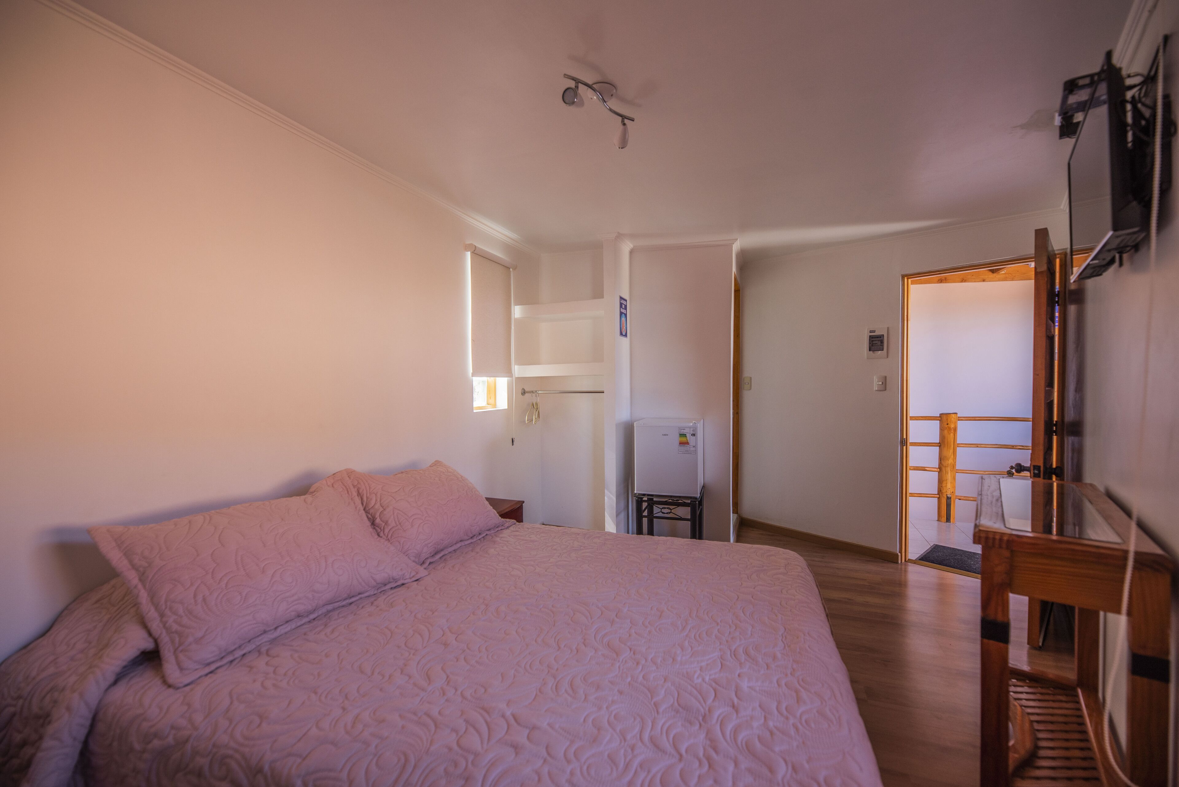 A bedroom with a bed, a desk, and a chair.