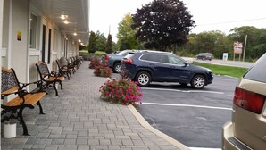 A building with a covered walkway, outdoor seating, and a parking lot. - Lakeview Inn (Blind River)