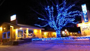 A motel with a large tree wrapped in blue lights, a sign for 'Lake View Motel', and a snow-covered ground. - Lakeview Inn (Blind River)