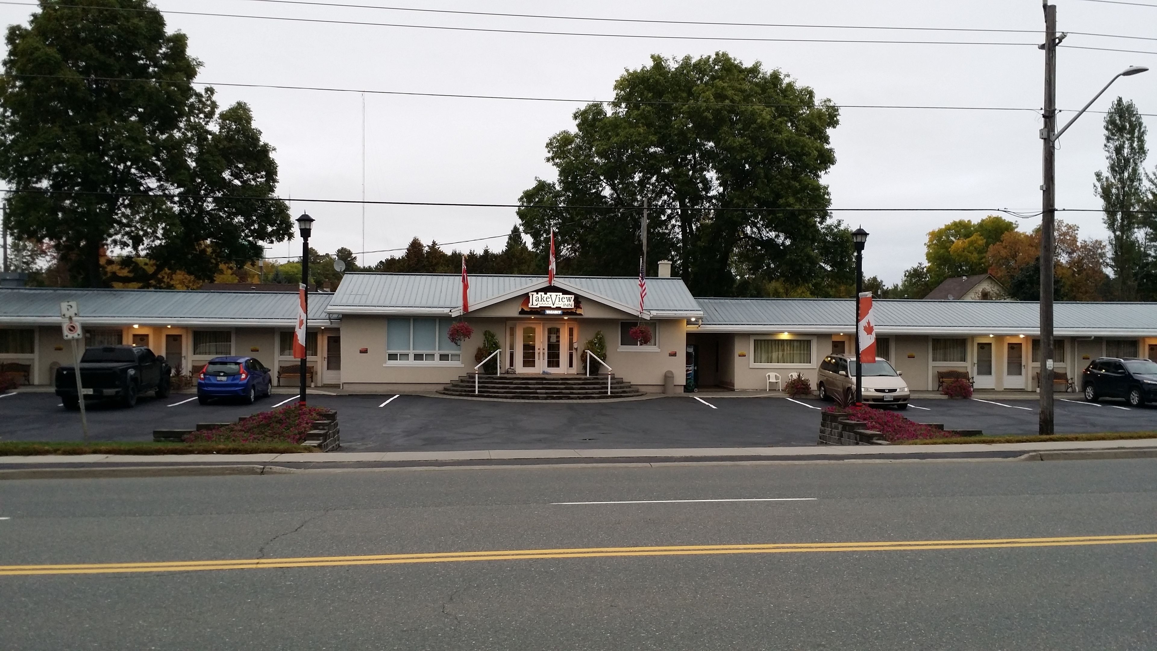 A motel with a central entrance, multiple parking spaces, and a flag in front.