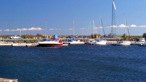 A marina with several boats docked, a wind turbine in the background, and a clear blue sky. - Lakeview Inn (Blind River)
