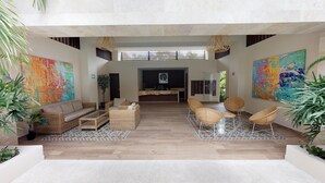 A spacious lobby with a reception desk, wicker furniture, and large abstract paintings. - Palmares by Playa Moments (Playa del Carmen)