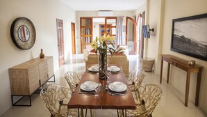 A dining area with a wooden table set for four, surrounded by chairs. A vase with flowers is placed in the center. - Plaza Marbella Granada Condiminiums (Granada)