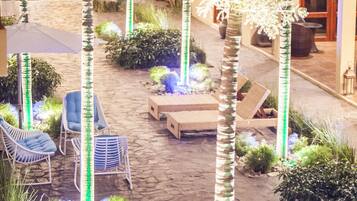 Un patio con palmeras, mobiliario exterior y plantas en macetas.