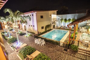 A pool area with a stone patio, lounge chairs, and a dining table.