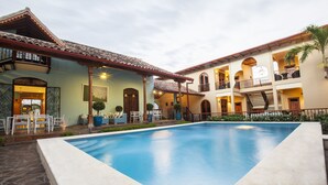 A courtyard with a swimming pool, outdoor seating, and a multi-story building with balconies. - Plaza Marbella Granada Condiminiums (Granada)