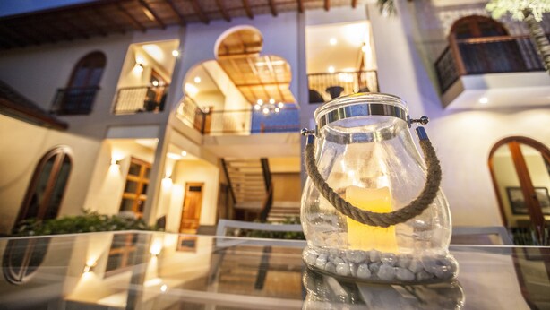 A glass candle holder with a rope handle on a reflective surface. - Plaza Marbella Granada Condiminiums (Granada)