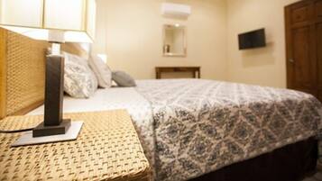 Habitación de hotel con una cama, una lámpara, un televisor montado en la pared y una puerta de madera.