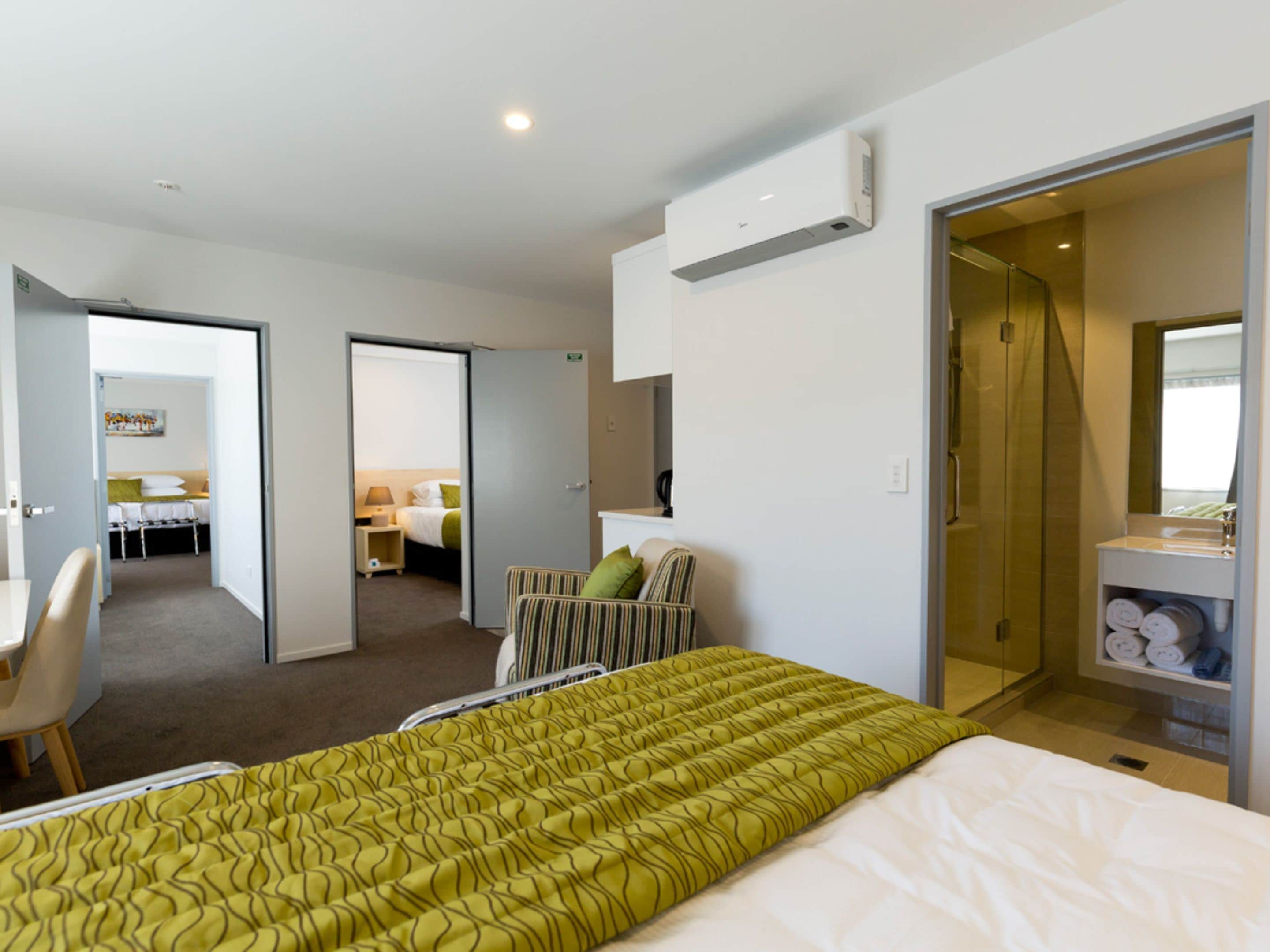 A hotel room with a bed, a chair, a desk, and a bathroom.