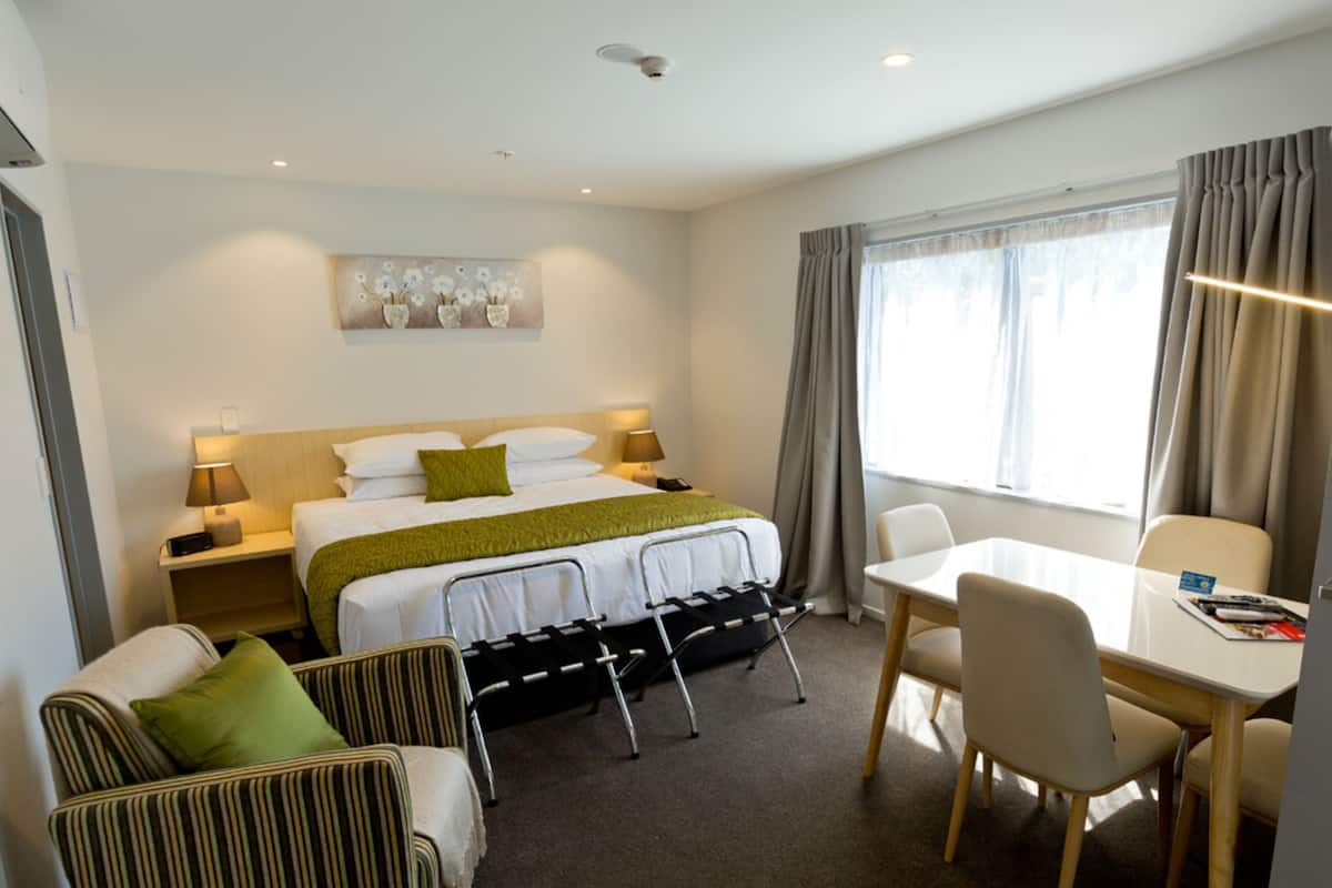 A hotel room with a bed, bedside tables, a desk, a chair, and a sofa.