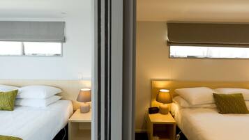 A hotel room with two beds, bedside tables, lamps, and a window with a view.