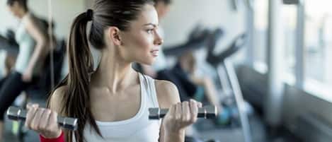 A gym with exercise equipment and a person lifting weights.