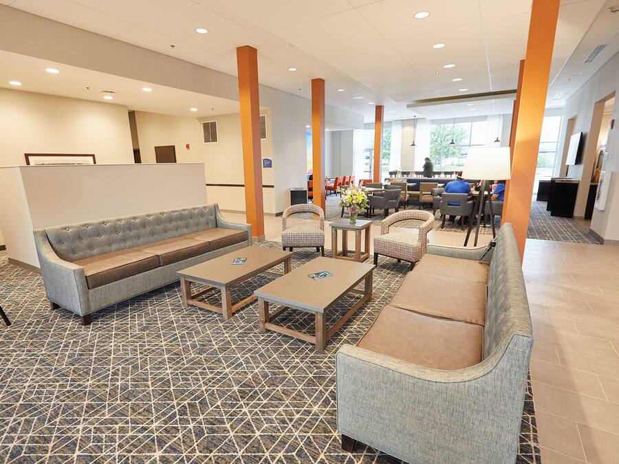 A hotel lobby with seating areas, a reception desk, and a view of the outdoors.