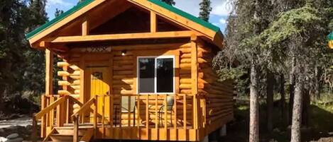 A log cabin with a porch and a staircase leading to the entrance.