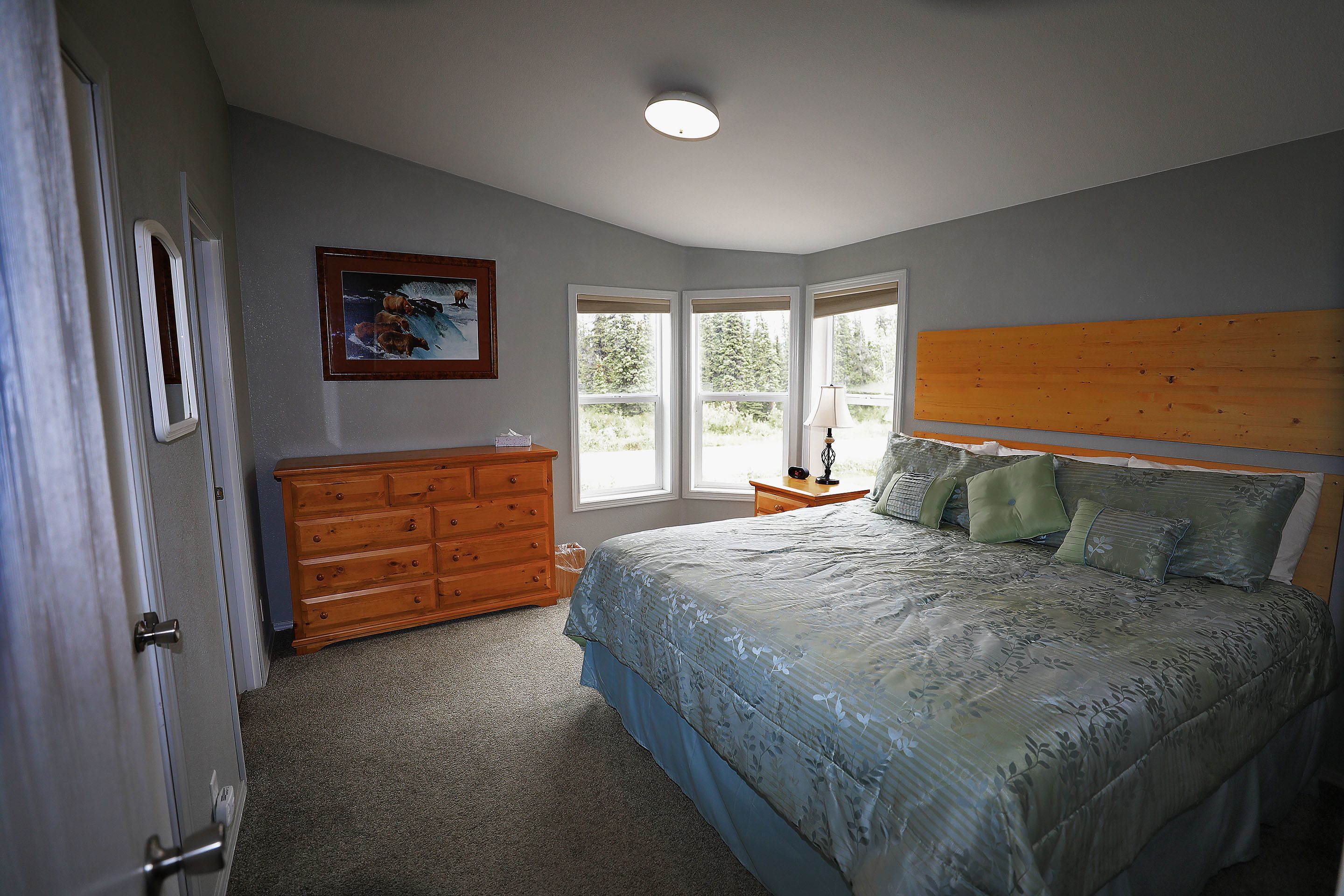 A bedroom with a bed, dresser, and windows.