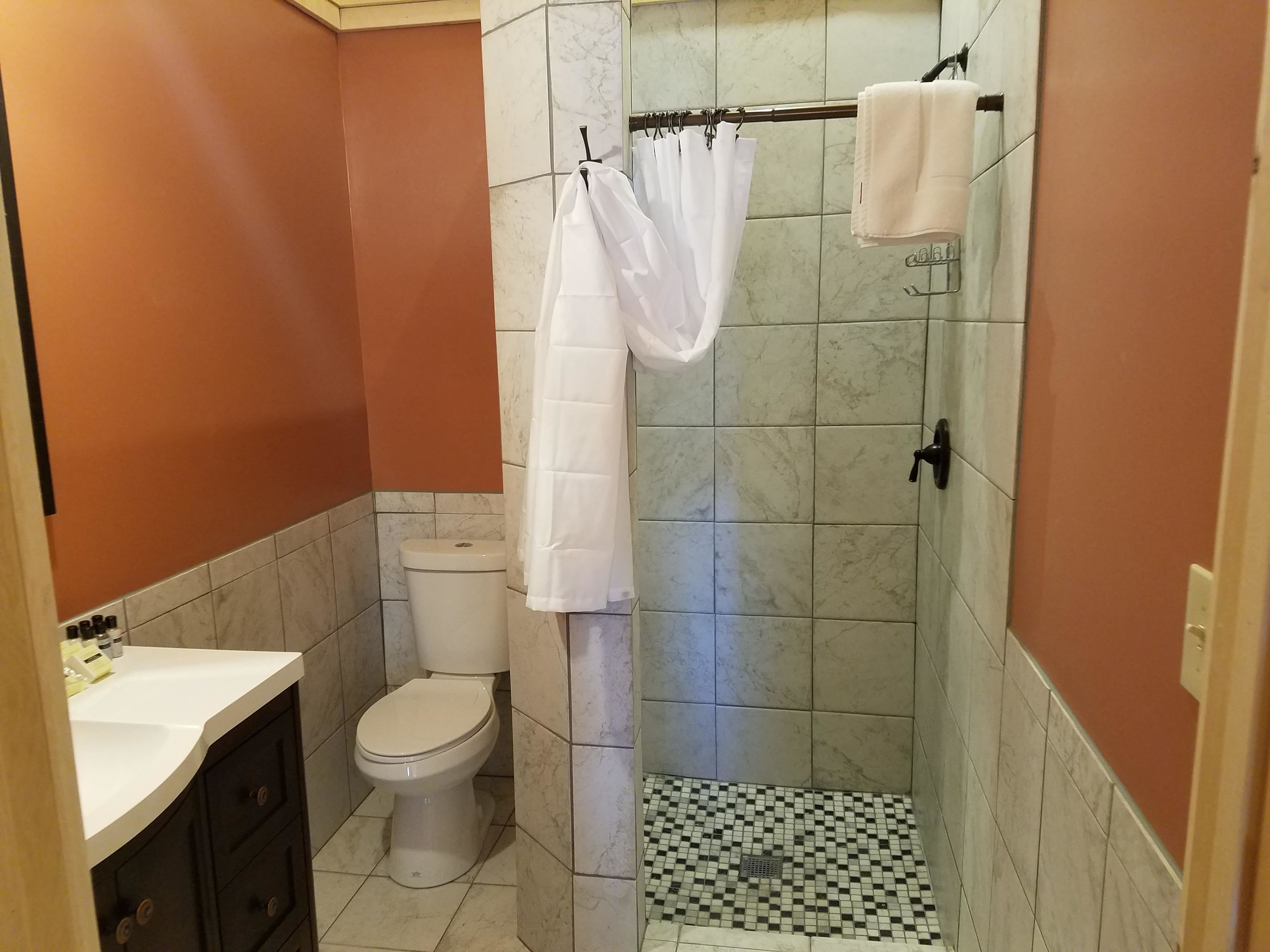 A bathroom with a toilet, a shower with a curtain, and a sink.