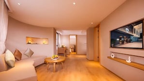 Ein modernes Wohnzimmer mit einer Couch, einem runden Holztisch und einem großen Flachbildfernseher an der Wand.