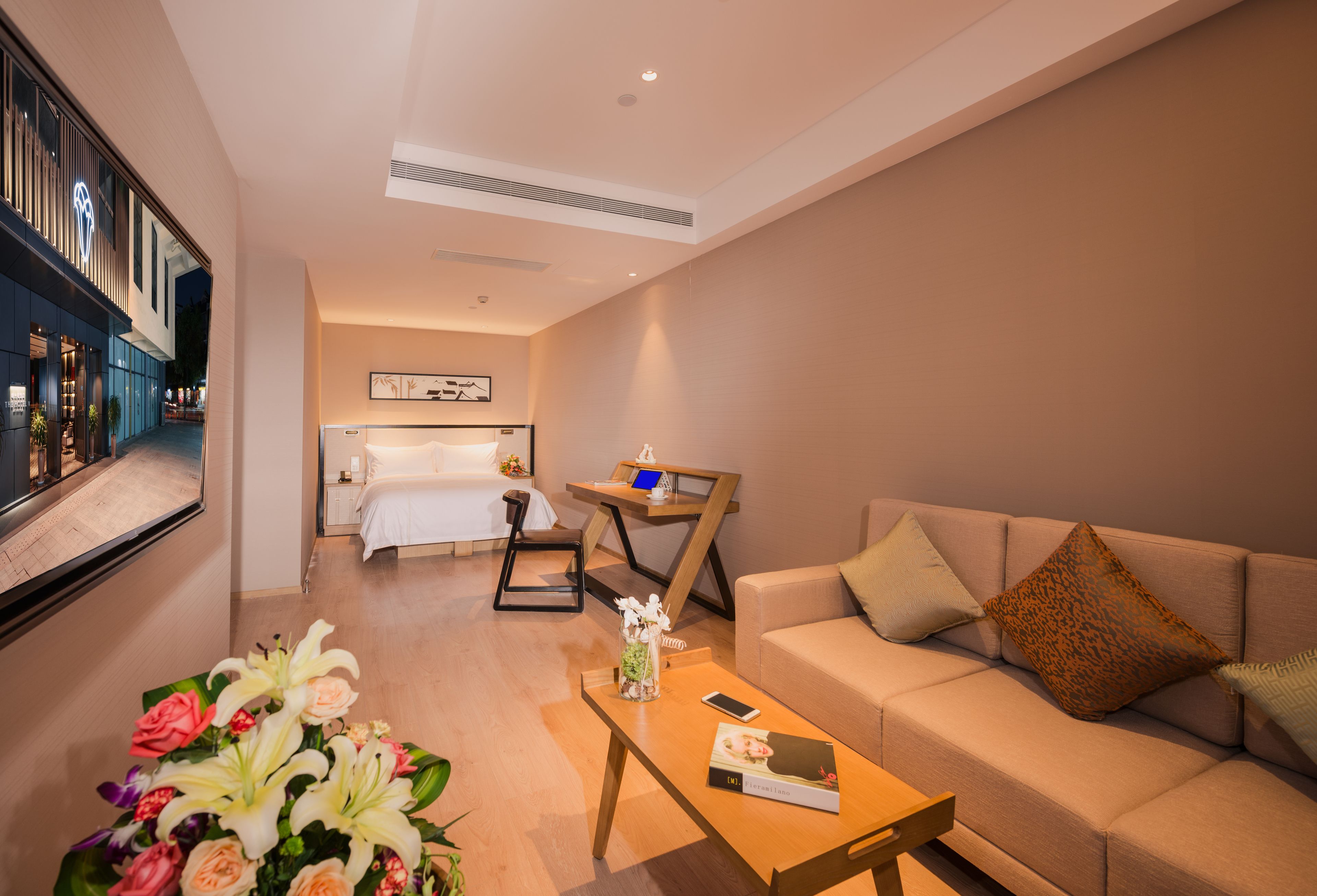 Una habitación de hotel moderna con sofá, mesa de centro, escritorio y cama.